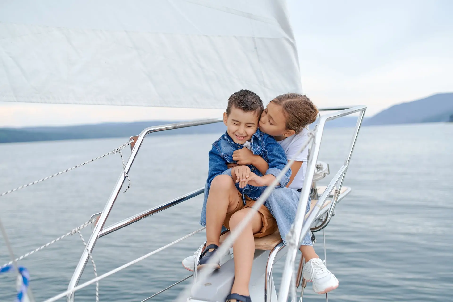 Dos niños felices abrazados en la proa de un velero durante una excursión en barco por Menorca