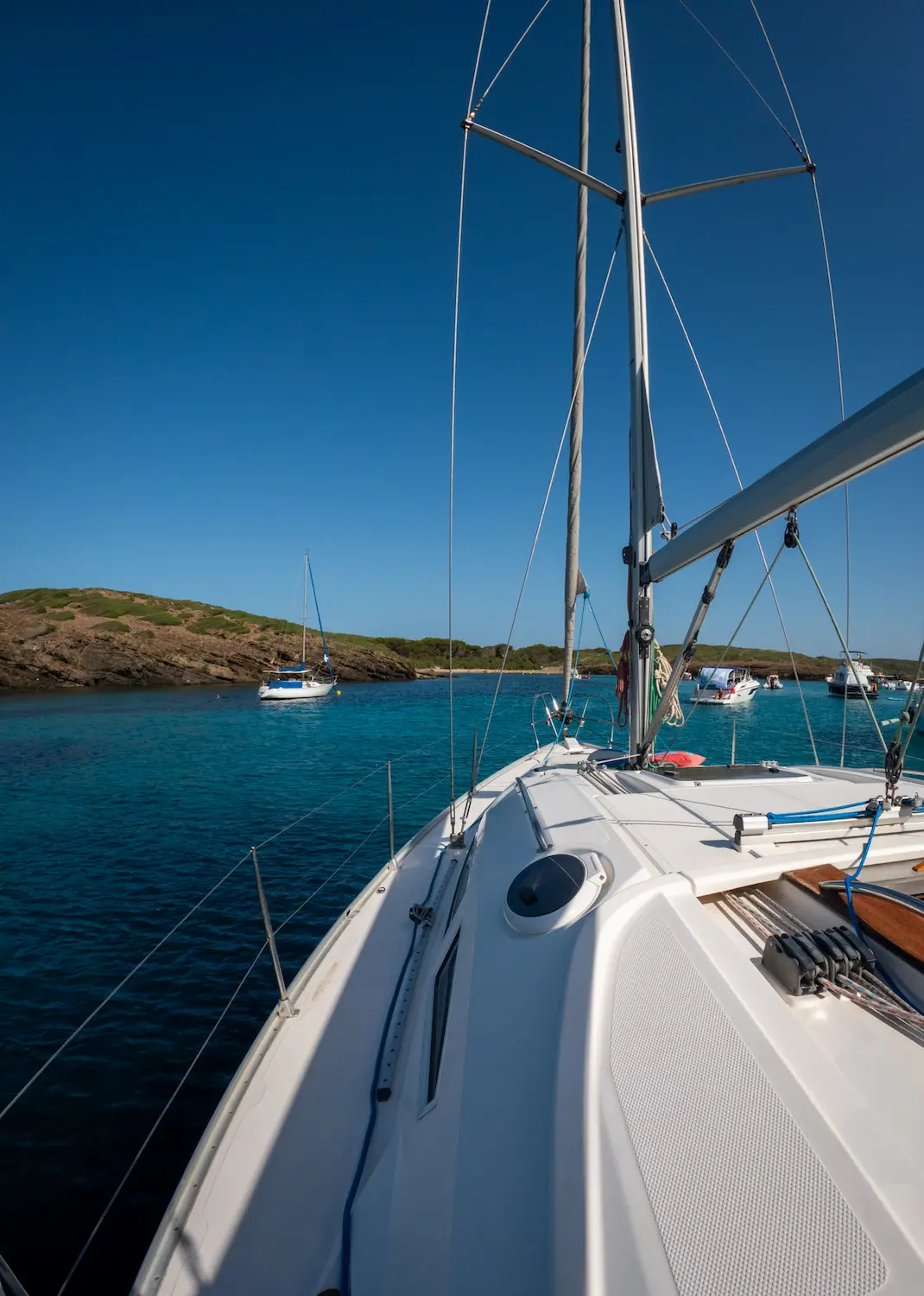 Bow of the sailboat anchored in a calm bay during a trip around Menorca