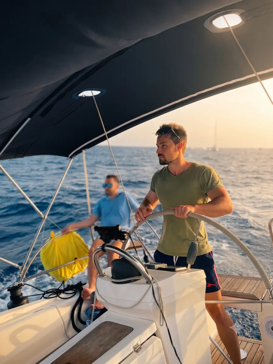 Sergi, propietario de Elan Menorca, al timón del velero al atardecer