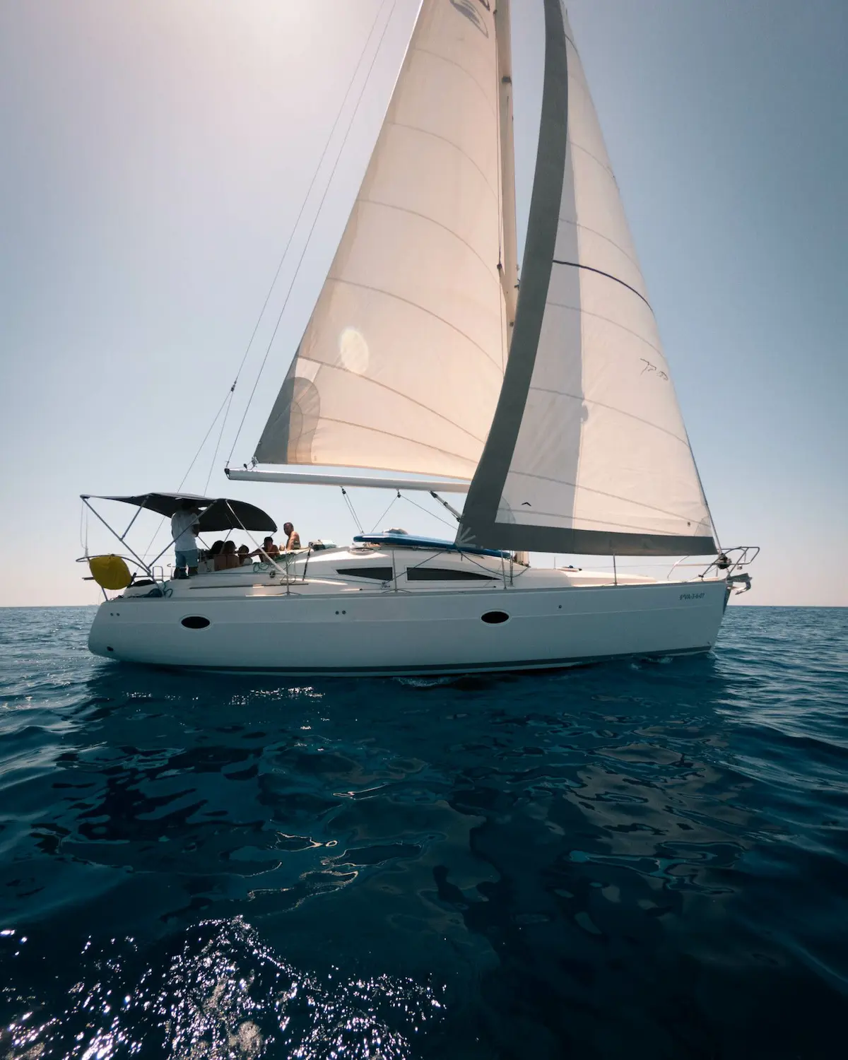 Velero Elan navegando a vela por Menorca, comparado con catamarán y lancha