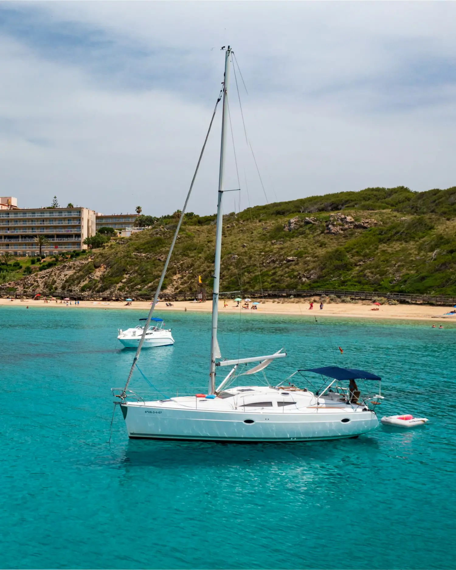 Sailboat anchored in front of a white sand beach in Menorca